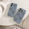 Two blue phone cases with bow designs on a white surface.