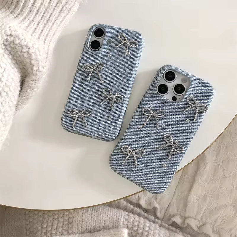 Two blue phone cases with bow designs on a white surface.