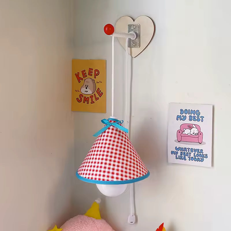 Heart-shaped wall lamp with a red and white checkered lampshade in a room setting.