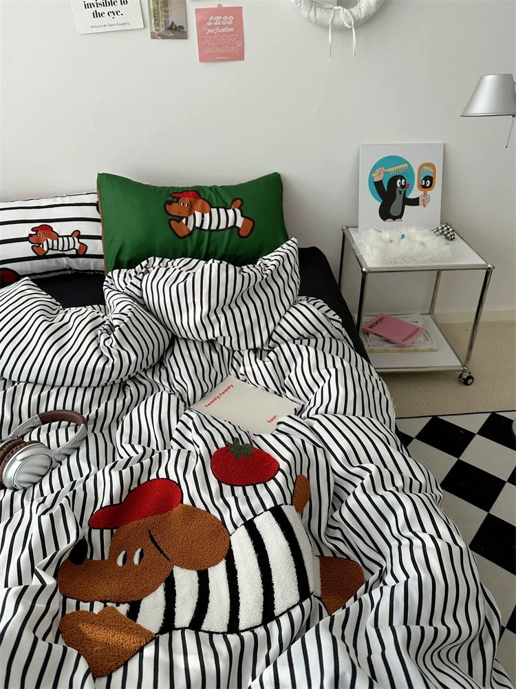 Bedroom with black and white striped bedding featuring cartoon characters, a nightstand with a lamp, and decorative items.