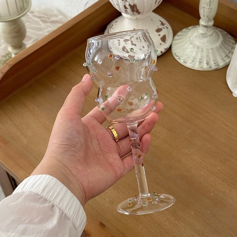 Hand holding a decorative glass with beads on a wooden surface