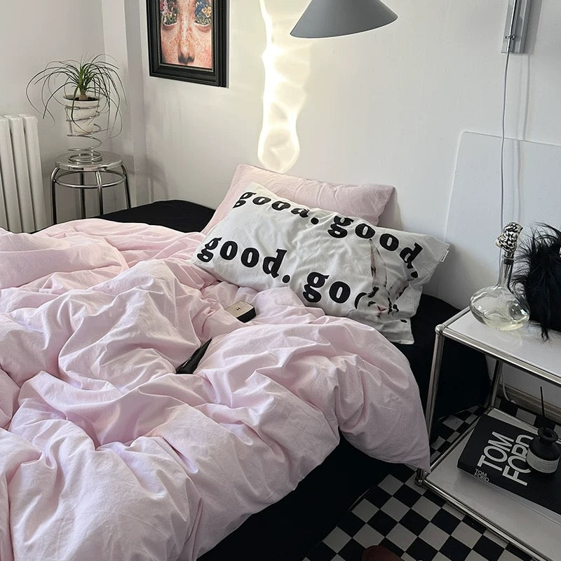 Pink aesthetic bedding for dorm room styled with checkerboard floor and books.