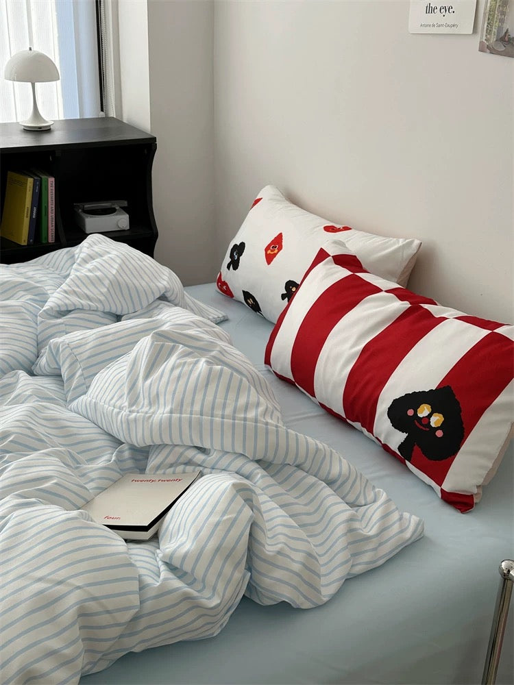 Bed with striped bedding and decorative pillows in a room setting