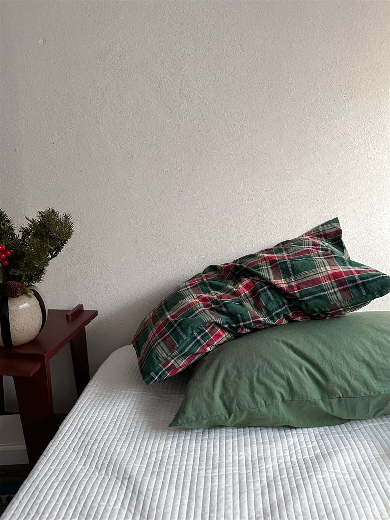 A green tartan pillowcase rests across a solid green pillowcase.
