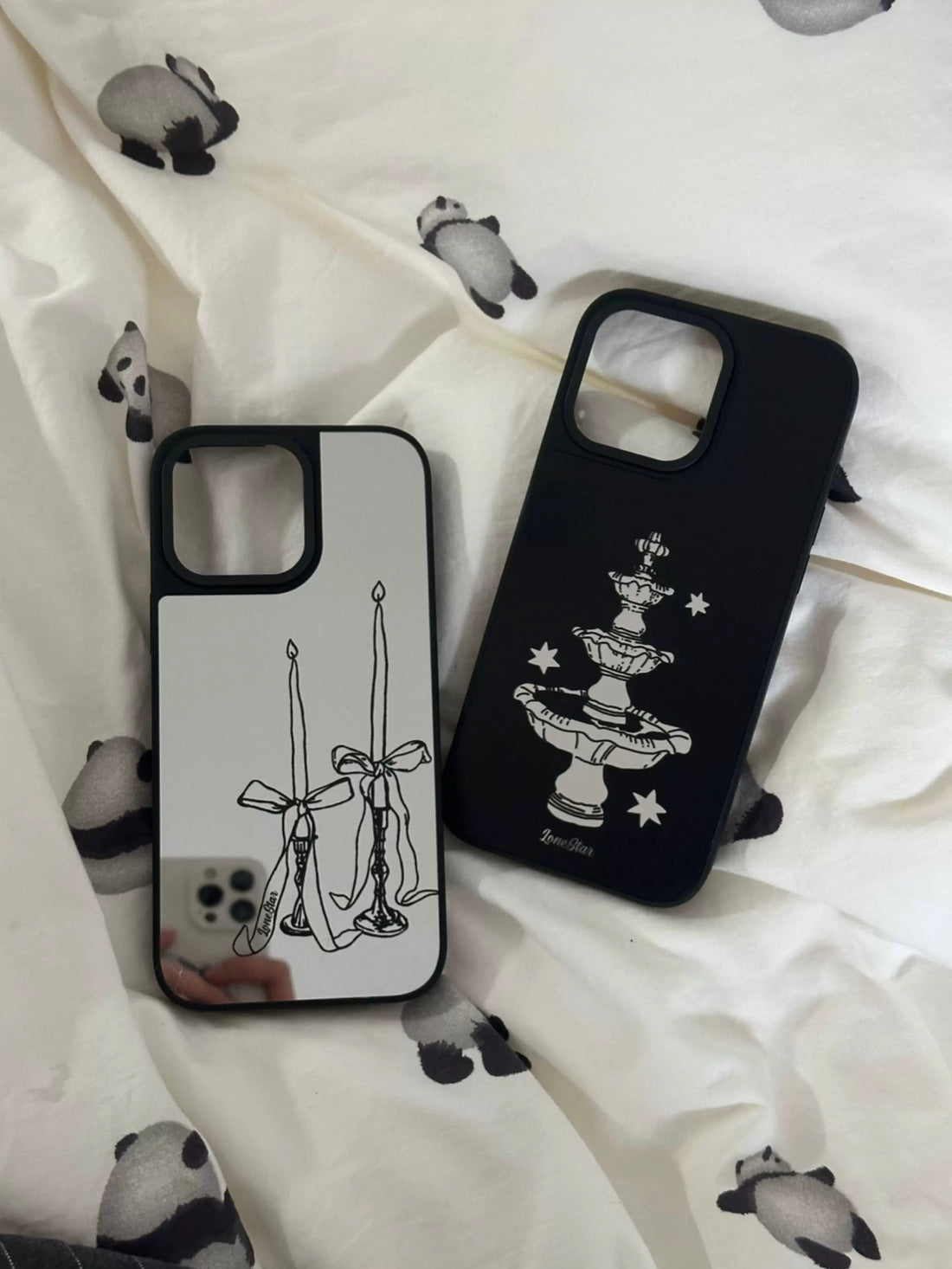 A dark coquette phone case pair with silver bow candles and a black star fountain, both edged in black.