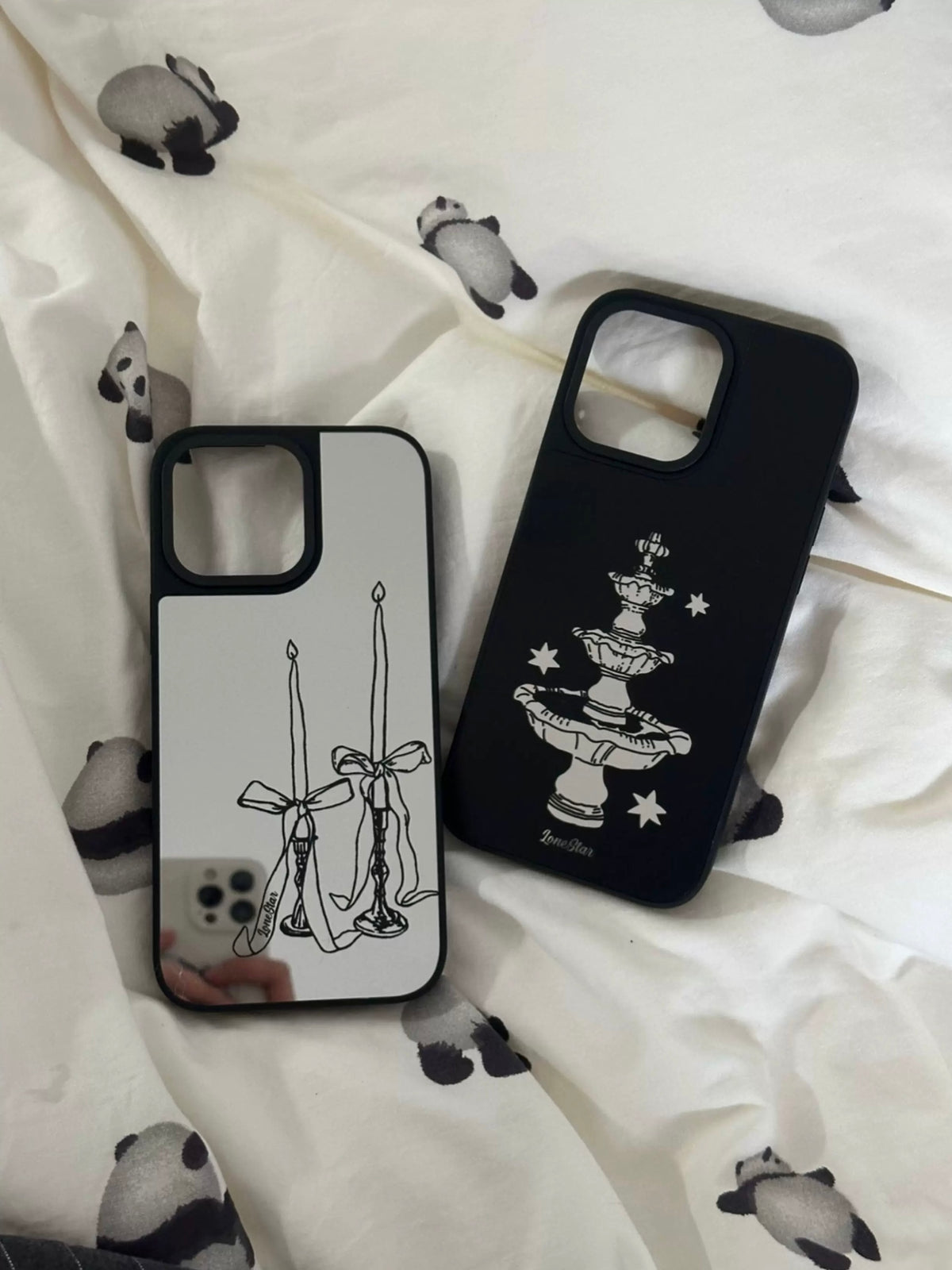 A dark coquette phone case pair with silver bow candles and a black star fountain, both edged in black.