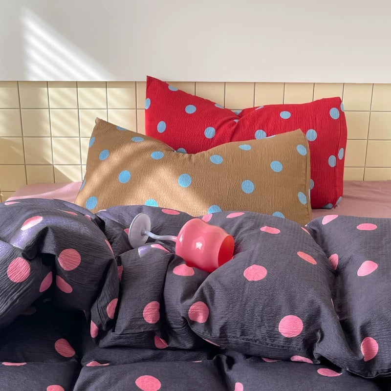 Gray pink polka dot bedding set displayed on bed with pillows and soft daylight