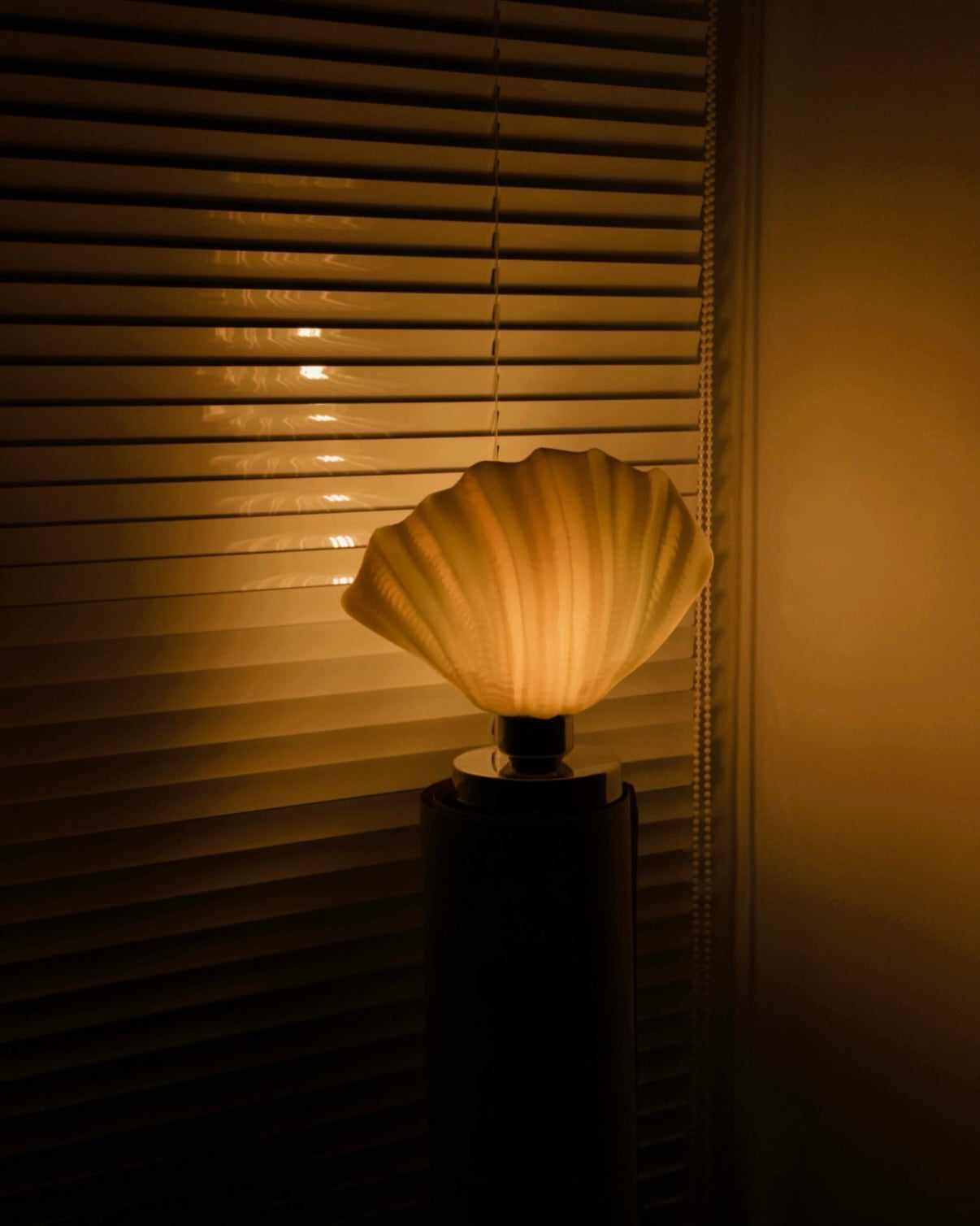 Shell-shaped lamp against a window with blinds