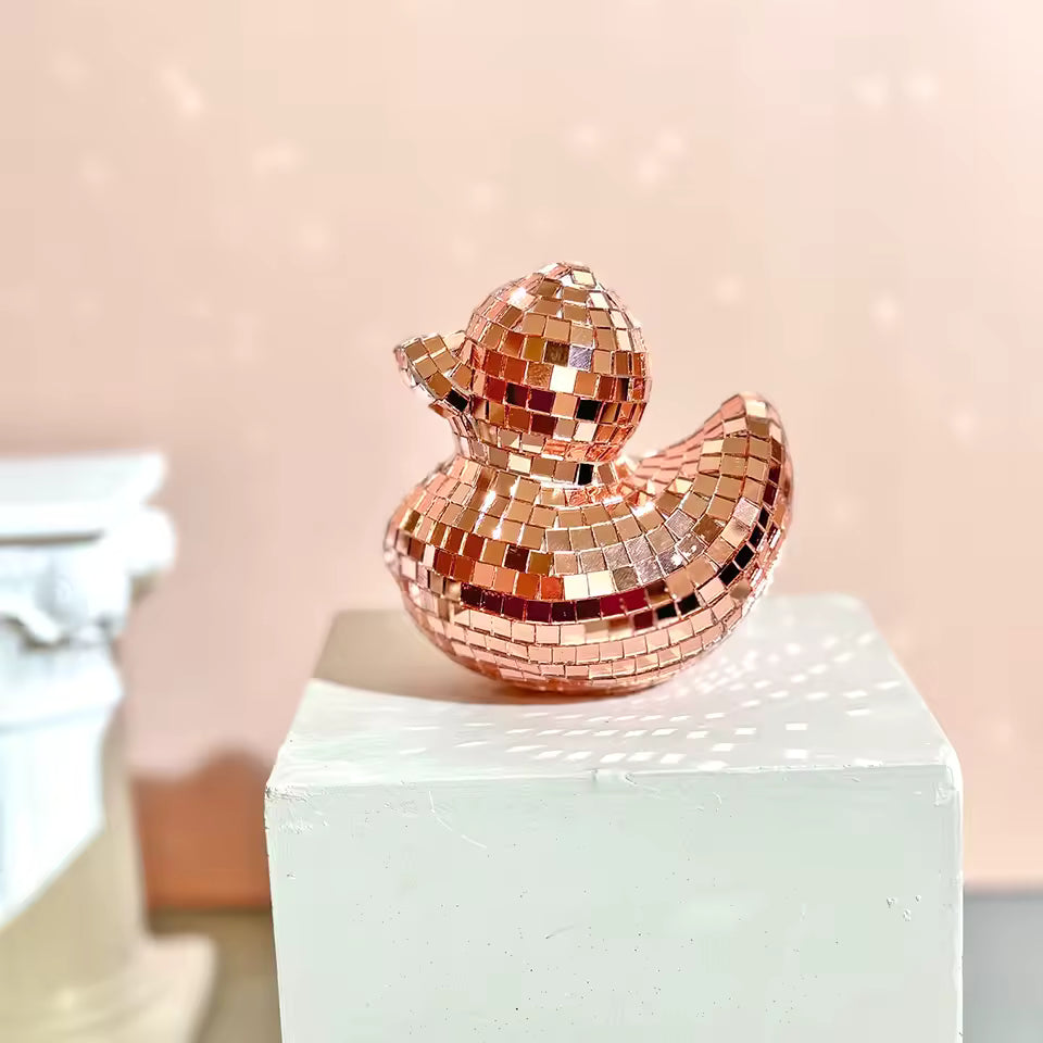 Rose gold mosaic rubber duck on a white pedestal with a soft pink background