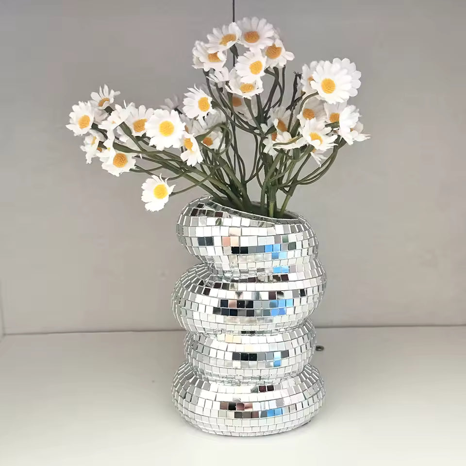Silver disco ball vase with white flowers on a plain background