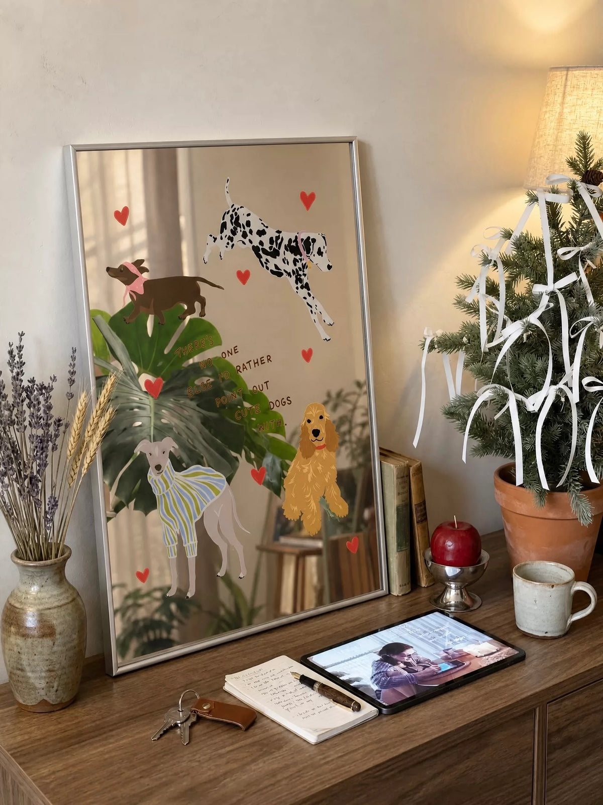 A dog illustration mirror leans on a desk, with red hearts and colorful dogs across the reflective surface.