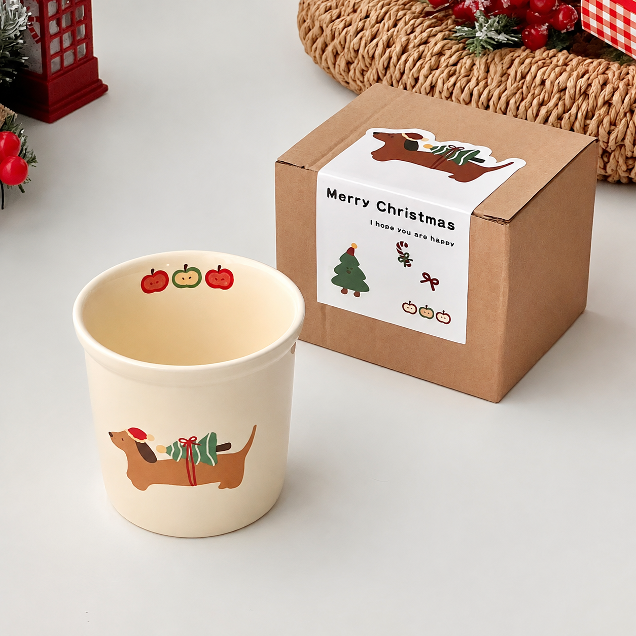 Ceramic mug with dachshund design next to a Christmas-themed gift box on a light surface.