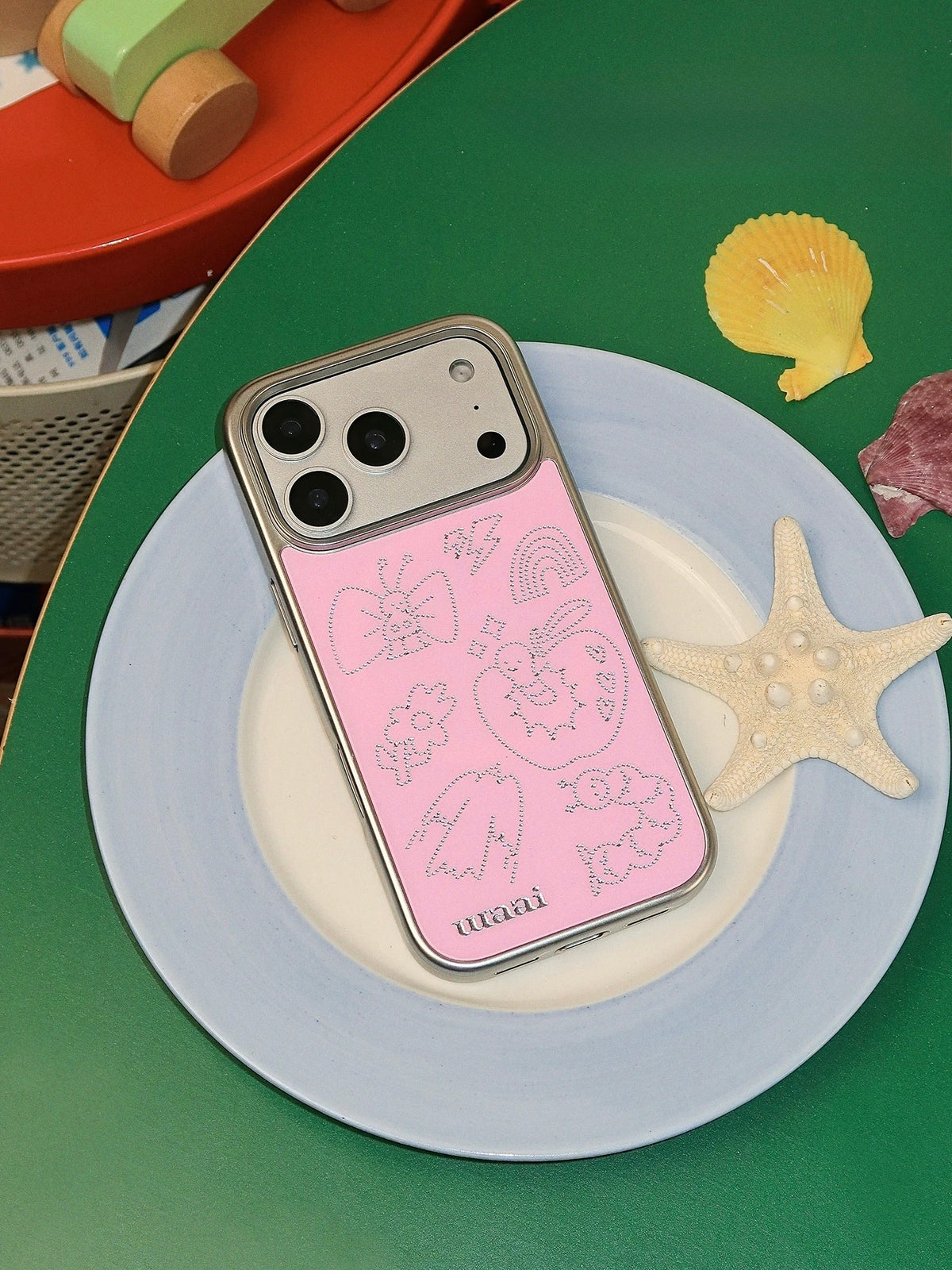 A doodle phone case in pink with fine silver butterfly, apple and candy outlines across the back.