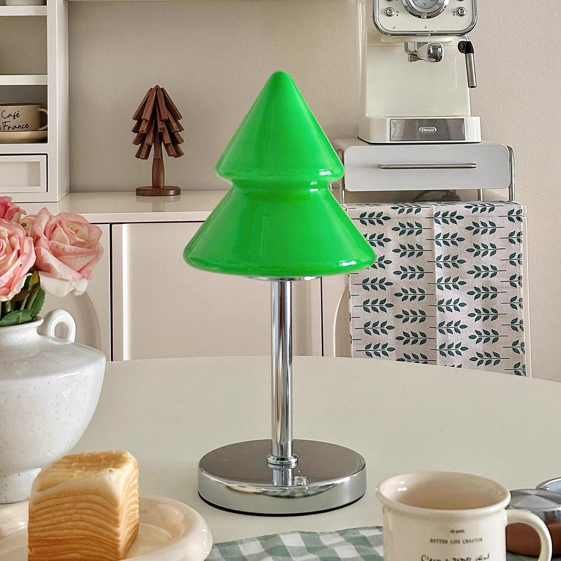 Green lamp on a kitchen counter with flowers and a coffee machine in the background