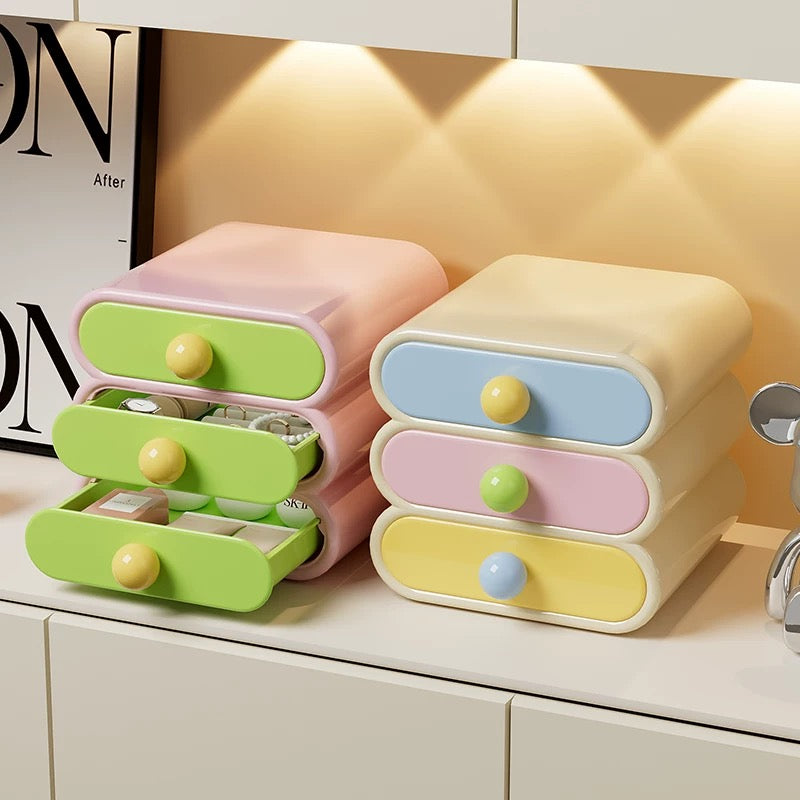 Pastel-colored storage drawers with yellow knobs on a shelf.