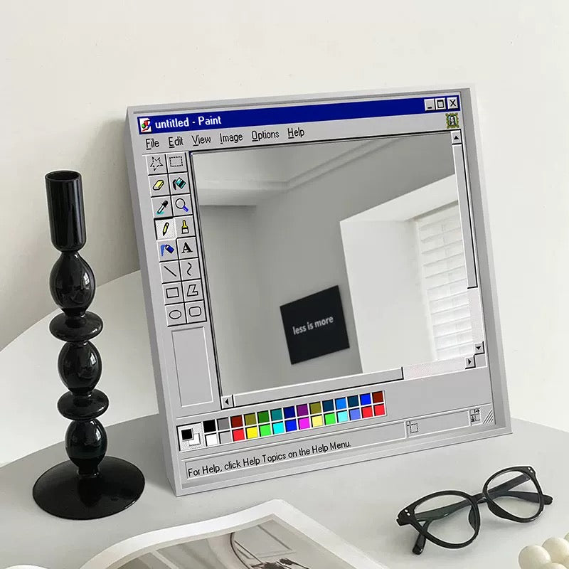 Digital mirror with retro computer interface on a white surface with a candlestick and glasses.
