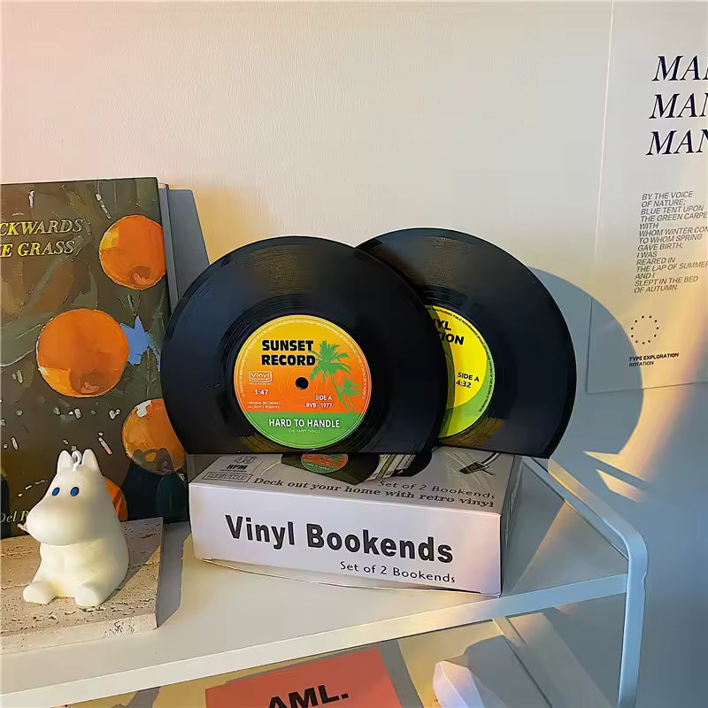Vinyl record bookends on a shelf with a small figurine and books in the background.