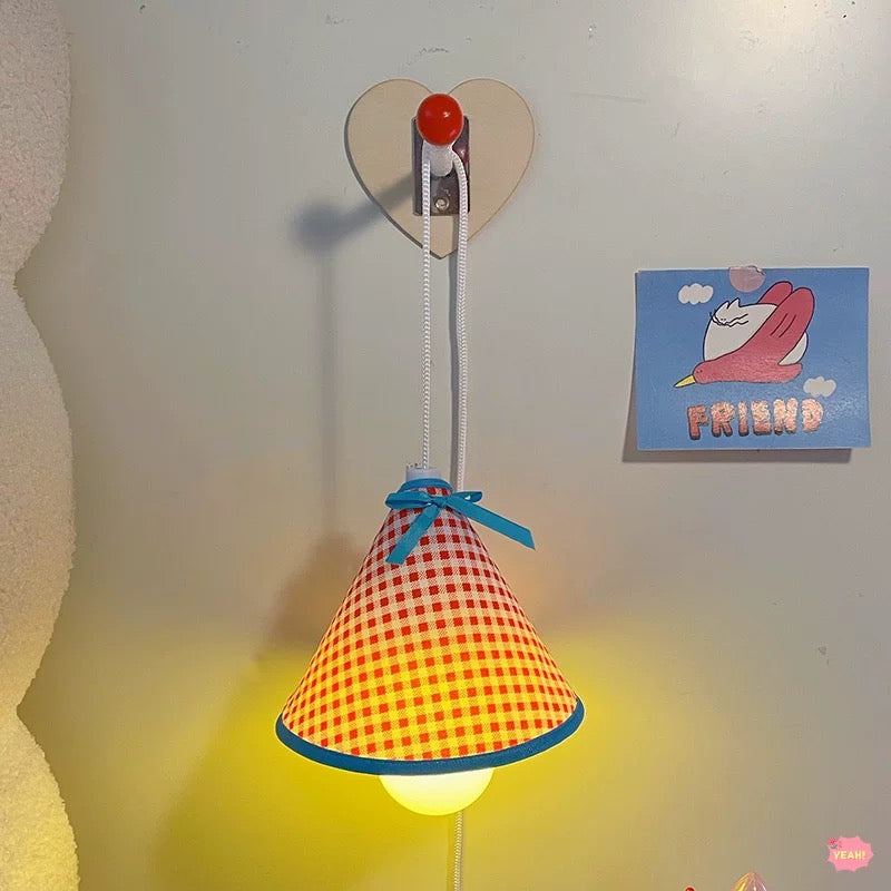 Colorful checkered lamp with a heart-shaped hook on a wall.