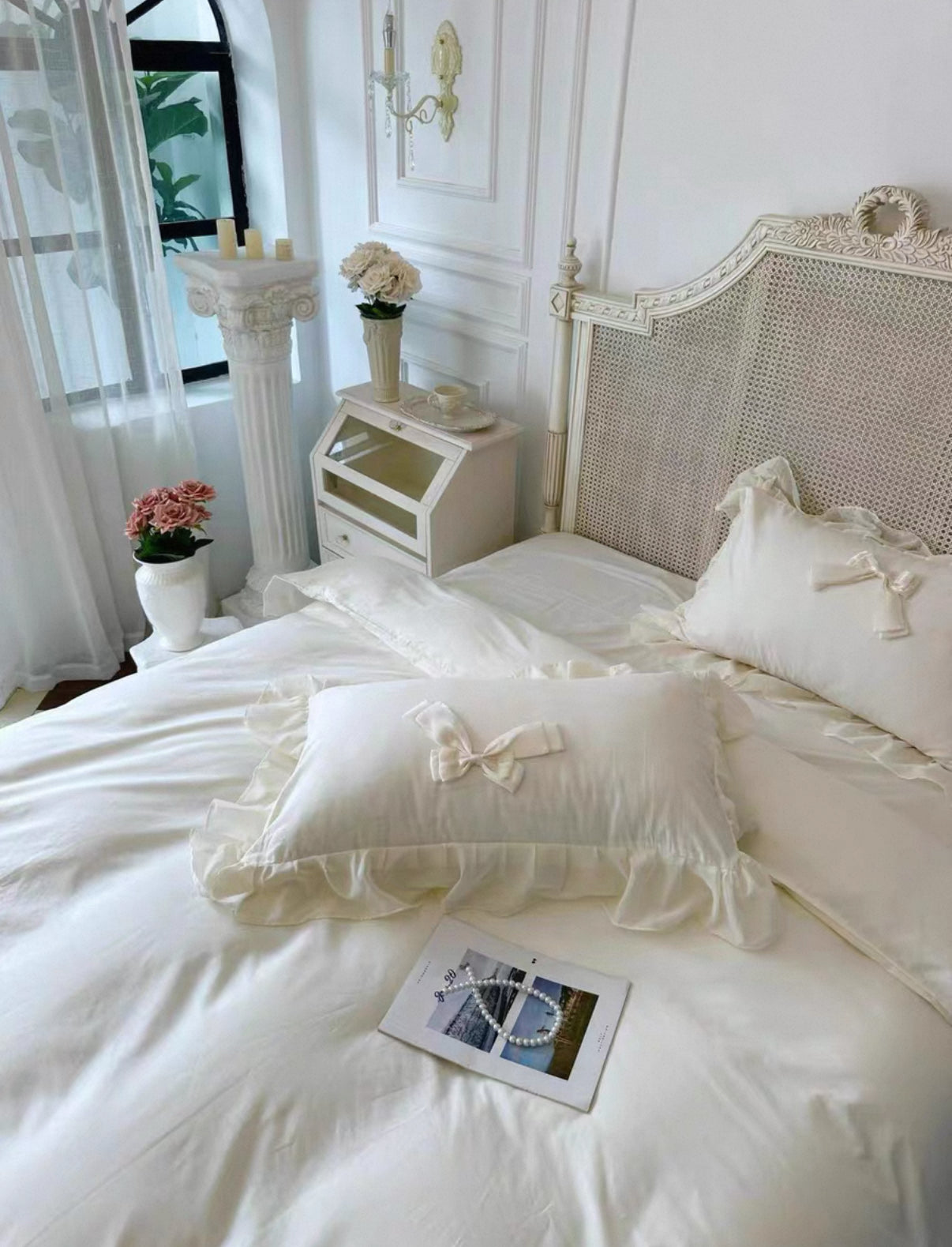 Neatly made bed with white bedding and decorative pillows in a bright bedroom.