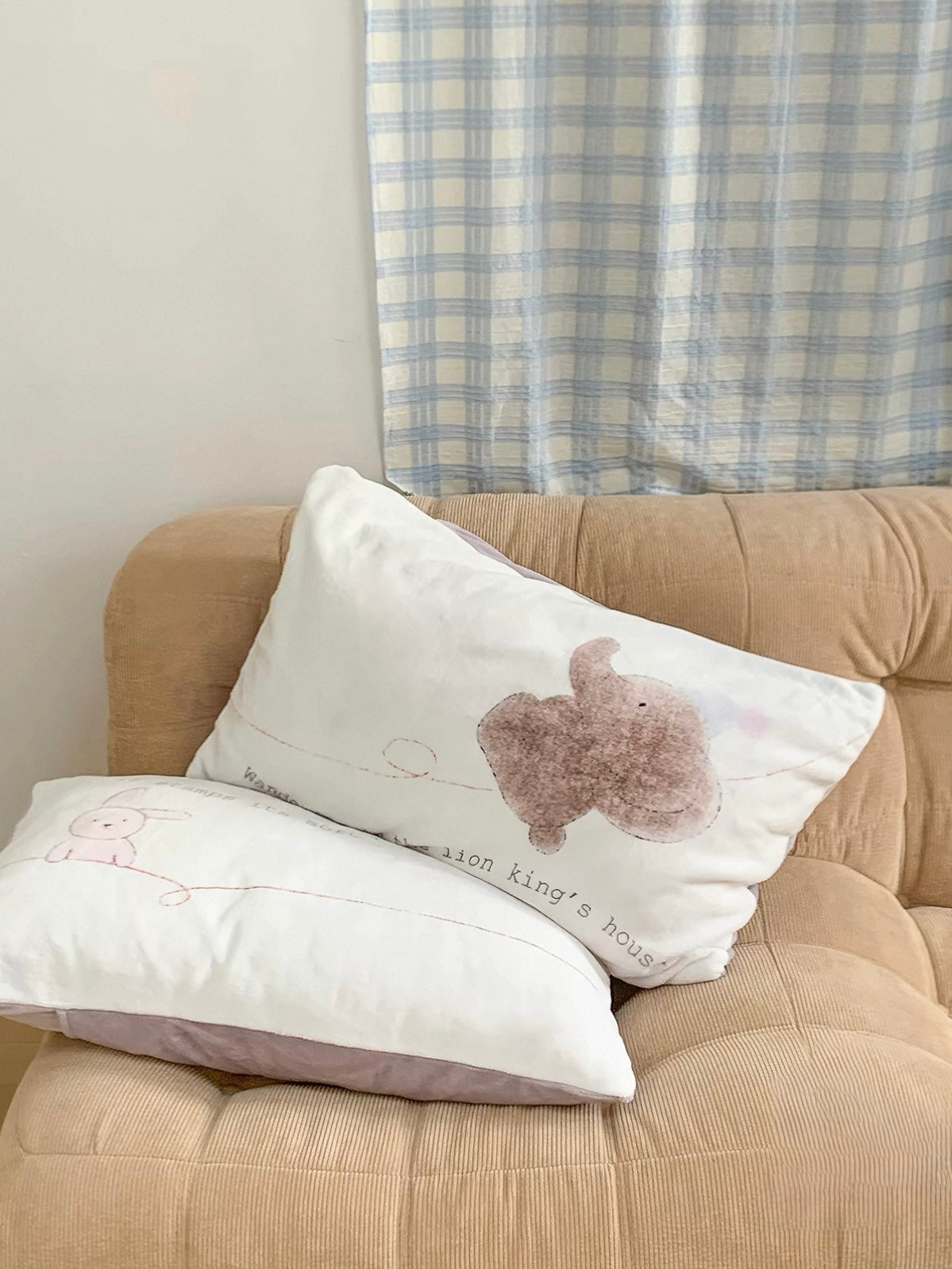 An elephant pillowcase sits on a tan chair above a pale rabbit pillowcase.