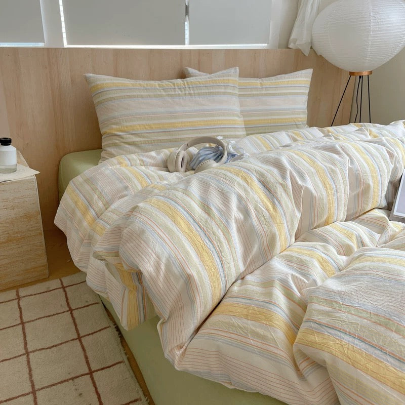 Bed with striped bedding in a room with wooden walls and a lamp.