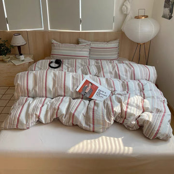 Bed with striped bedding and a magazine on a wooden nightstand in a room.
