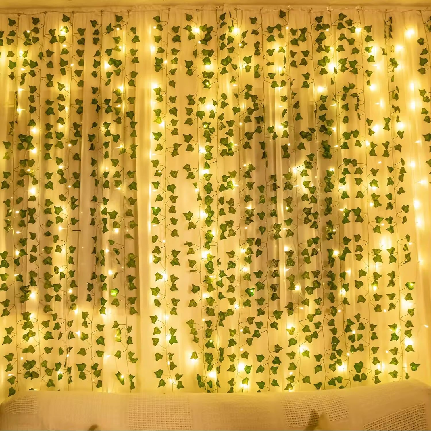 Close-up of green silk leaves wrapped around a glowing LED light string, ideal for fairycore vibes.