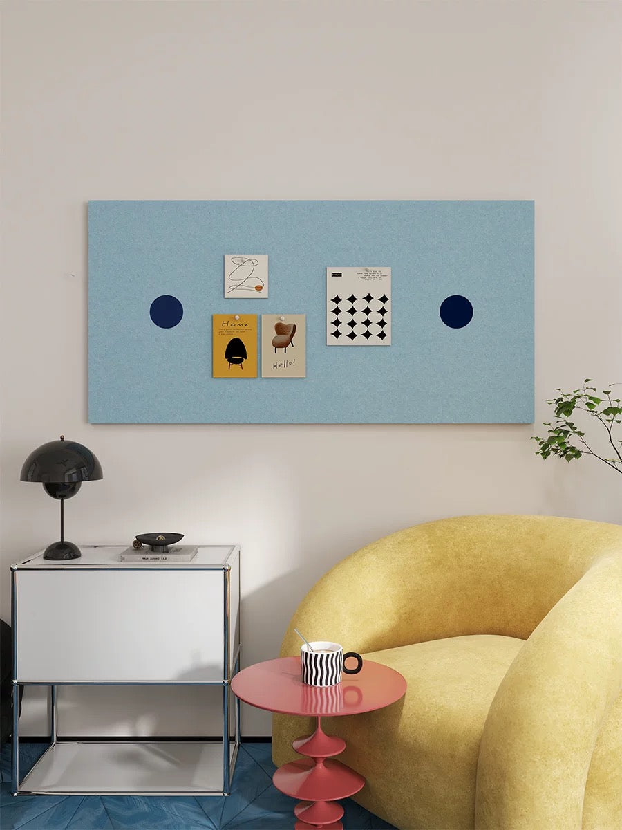 Light blue pin board for photos above a white cabinet with a black table lamp.