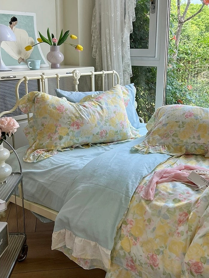 Floral gauze bedding with rose-print pillows and a blue sheet near the headboard