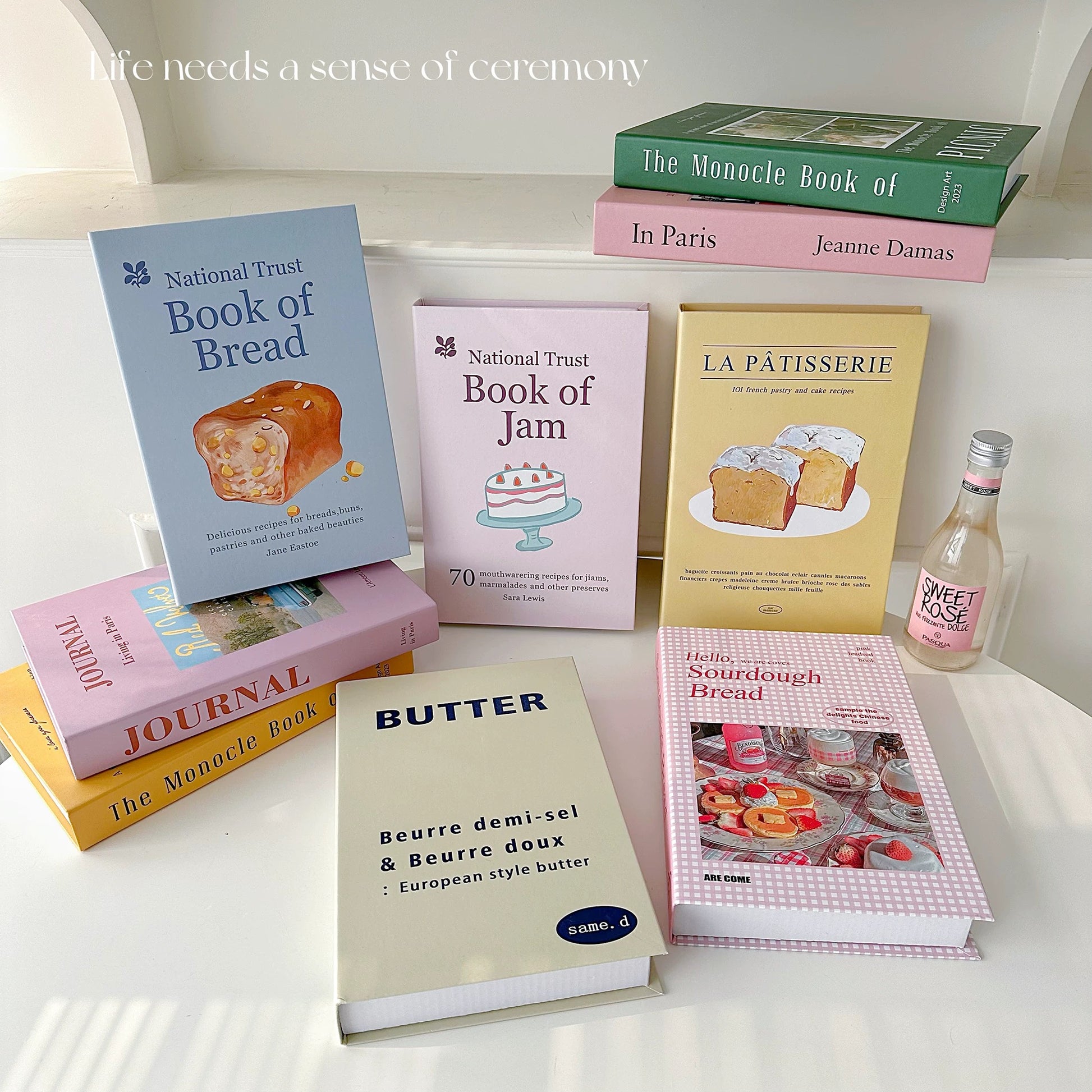 Collection of books on a surface with a bottle of Sweet Rose wine.