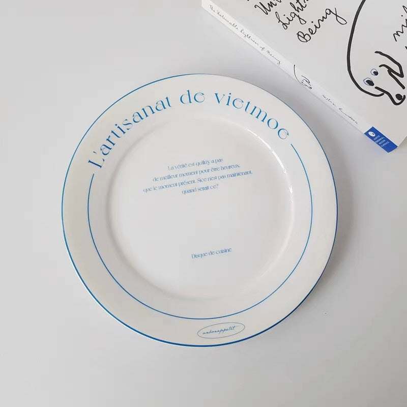 Shallow white French bistro plate with blue printed lettering and thin blue circular border detail