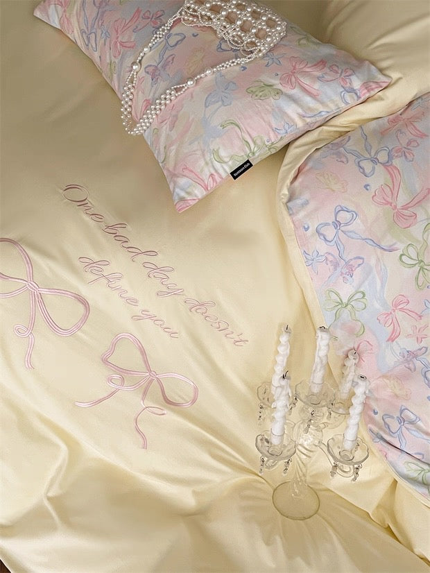 Decorative bedding set with embroidered text and decorative pillows on a beige background