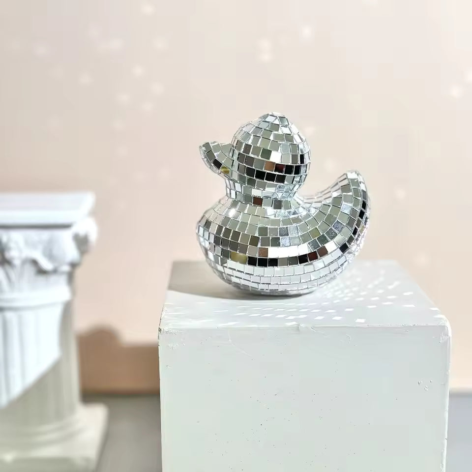 Silver disco duck on a white pedestal with a blurred background