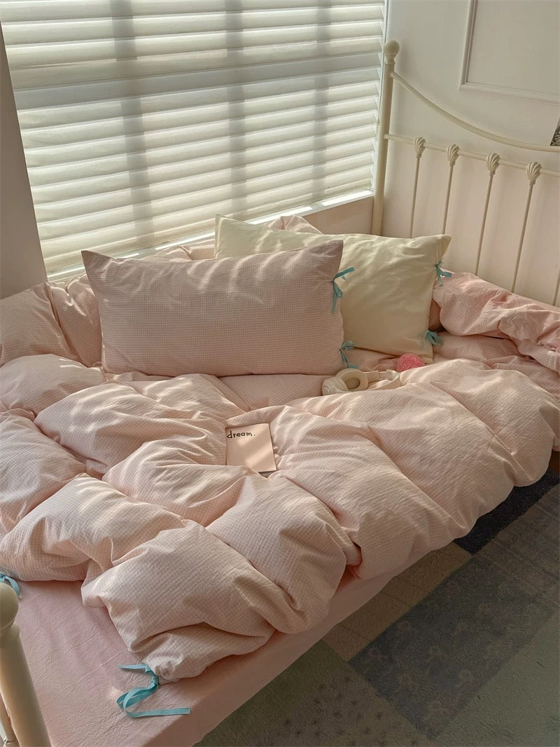 Bed with pink bedding and pillows in a softly lit room