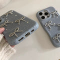 Two gray phone cases with bow designs on a light background