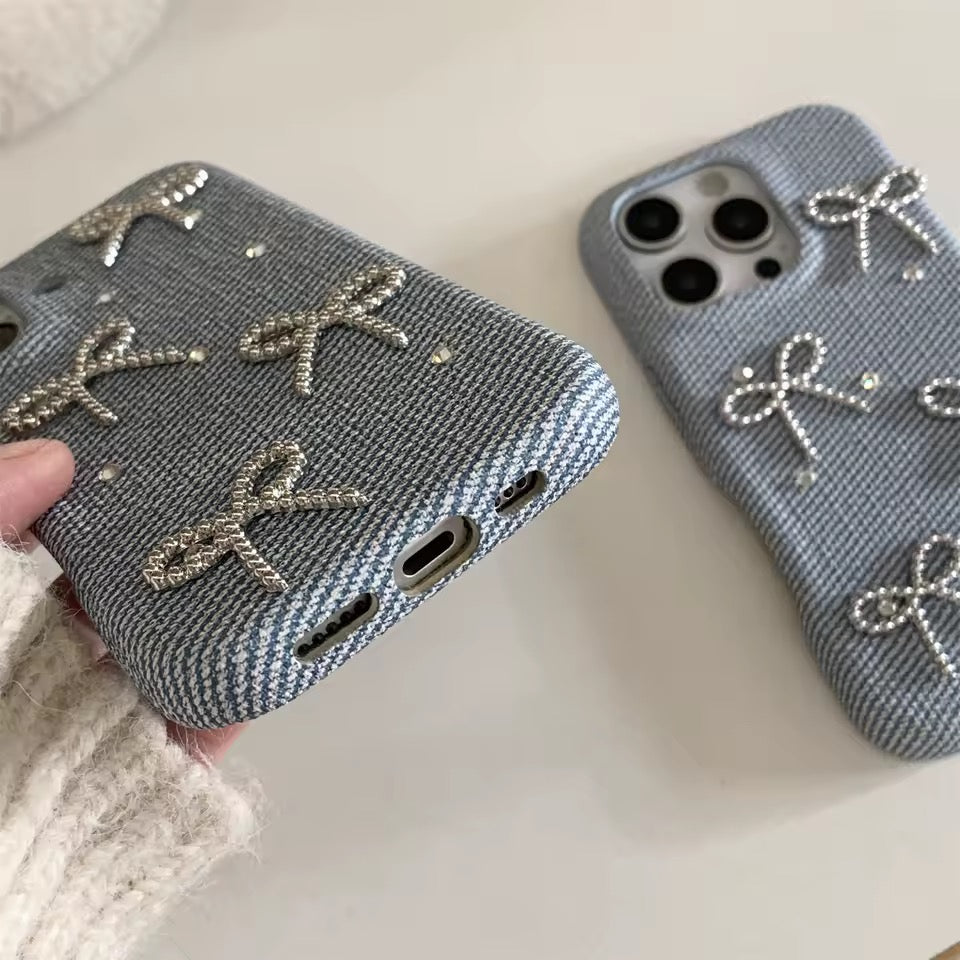 Two gray phone cases with bow designs on a light background