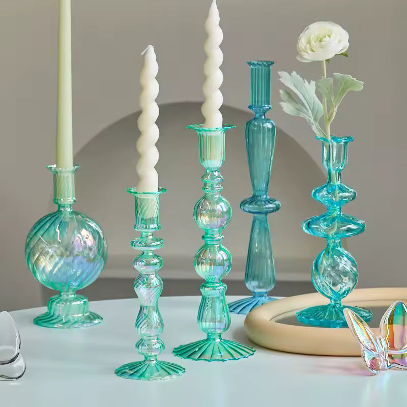 Collection of decorative glass candle holders and vases on a table.