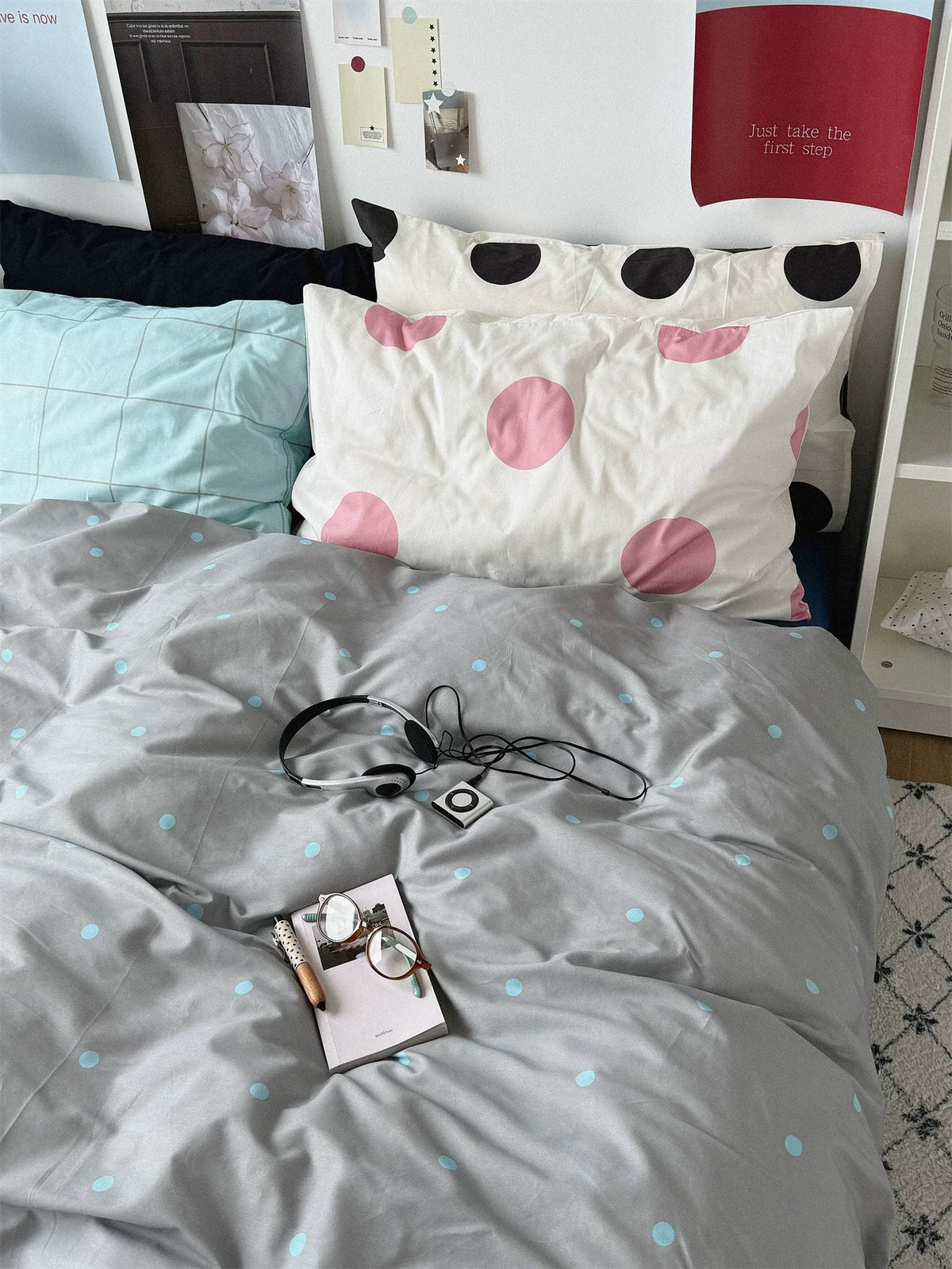 Gray blue polka dot bedding set with a blue sheet and layered check and dot pillows.