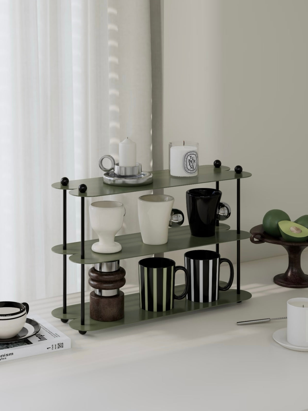 A green display shelf with black ball details is shown at an angle, holding cups and candles on open tiers.