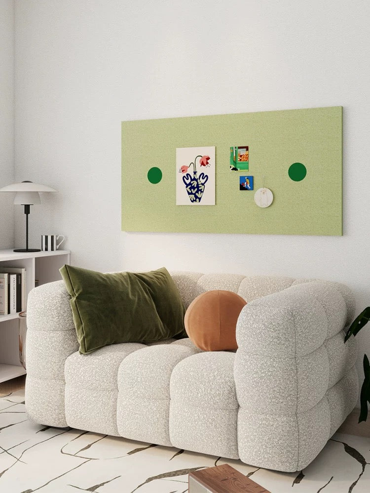 Green pin board with dark green circles above a white living room sofa, viewed at an angle.