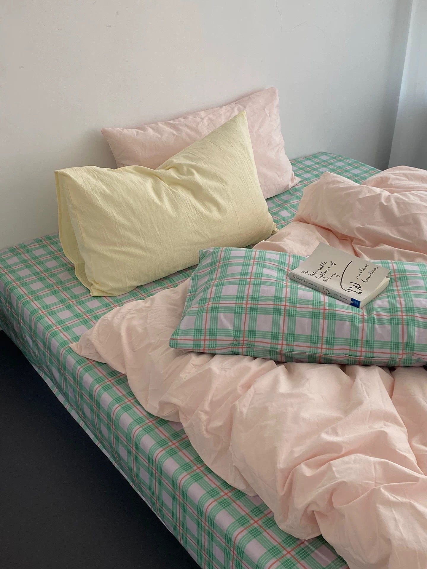 Bed with pink and green checkered bedding and pillows.