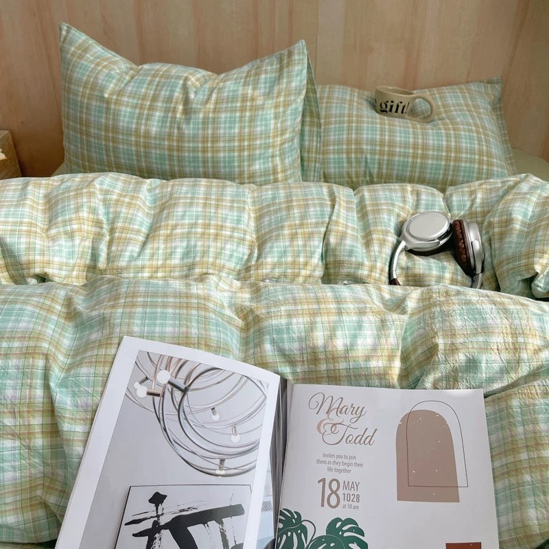 Plaid bedspread with a stethoscope and open magazine on a bed.