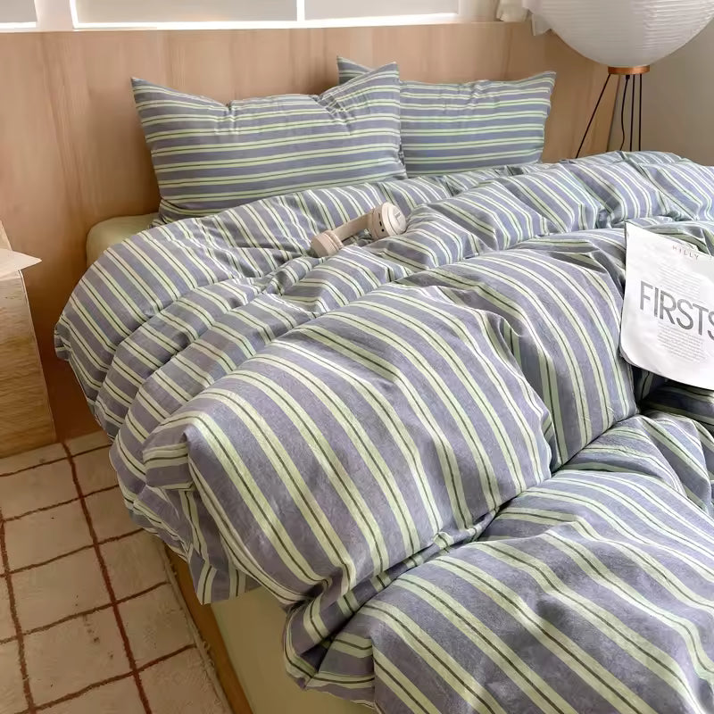 Striped bedding set on a bed with pillows and a visible brand name.