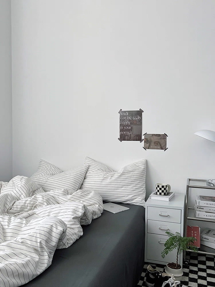 Modern bedroom with a bed, nightstand, and decorative items on a white wall.
