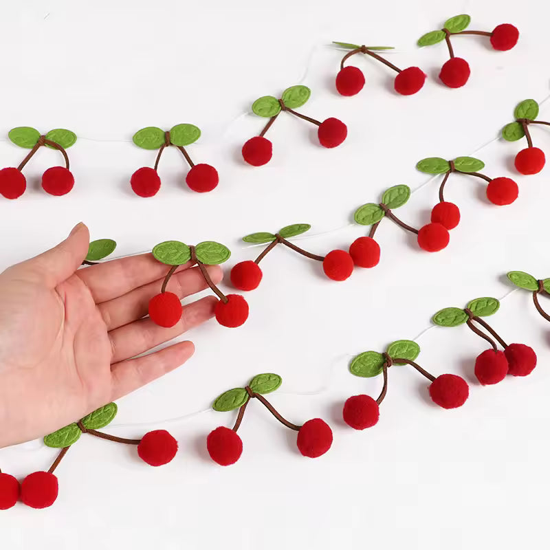 Red berry garland with green leaves on a white background, with a hand for scale.