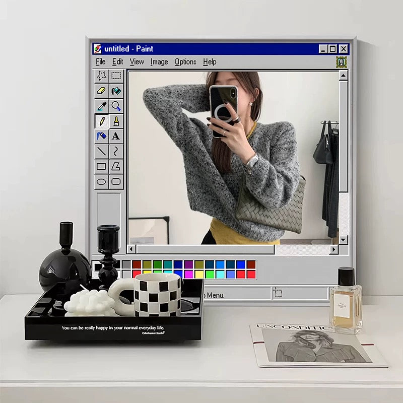 Person taking a mirror selfie with a computer screen displaying an image editing software.