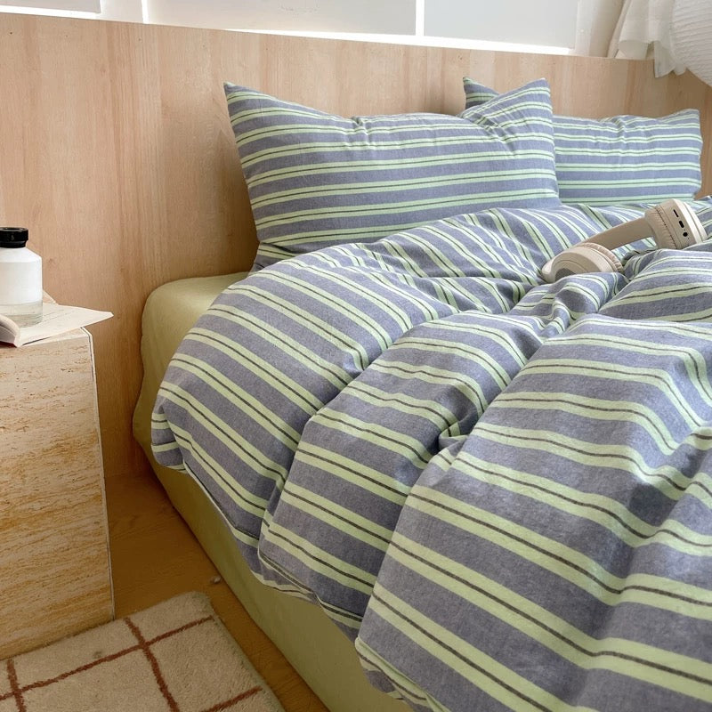 Striped bedding set on a bed with pillows and a visible brand name.