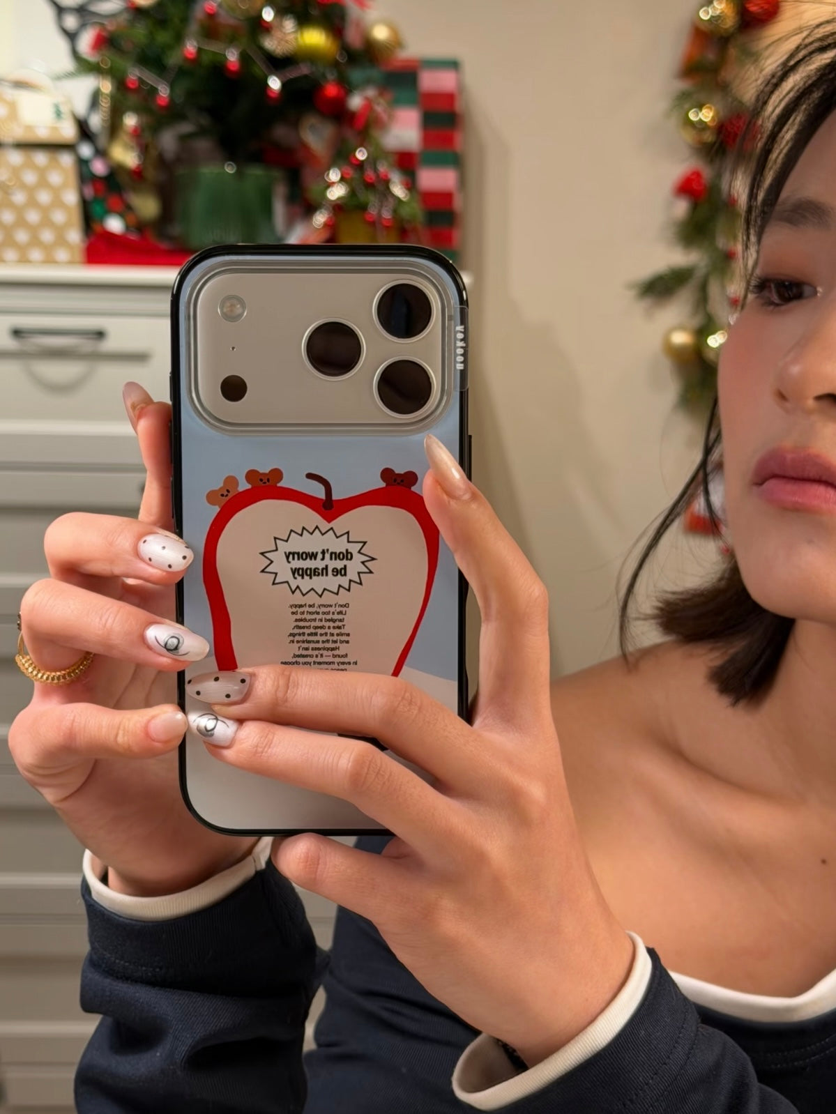 A Kawaii apple phone case is held in a mirror selfie, with tiny bears above the red fruit and a pale blue back.