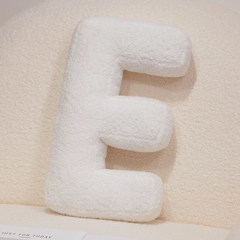 White letter 'E' pillow on a light beige background