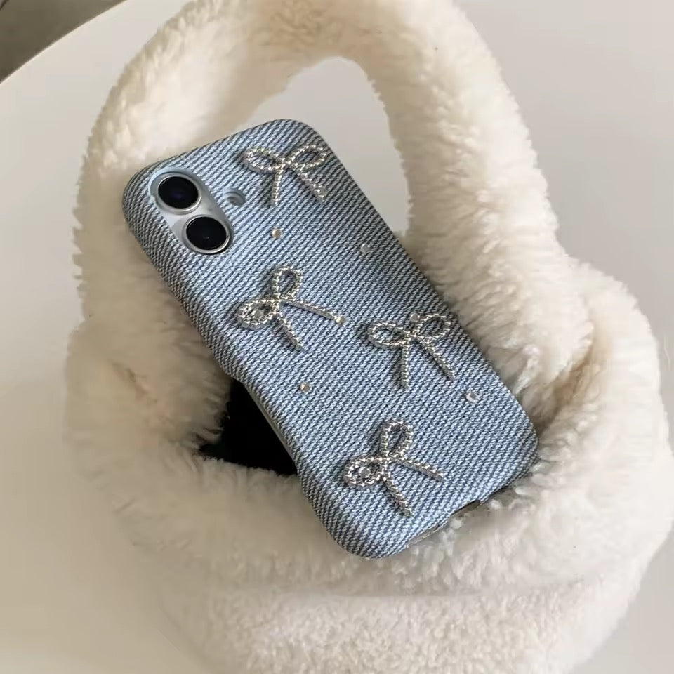 Phone case with decorative bows on a fluffy white surface